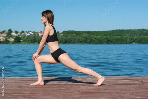 Girl in shorts and sports bra in sport on the dock at the lake.