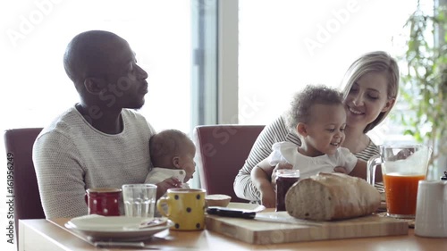Young interracial family with little children having breakfast. photo