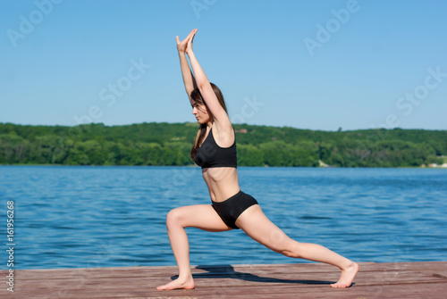 Girl in shorts and sports bra in sport on the dock at the lake.