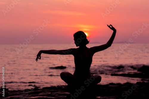 Woman silhouette sitting in lotus position on sunset sea background back lit © whiteandlight.com