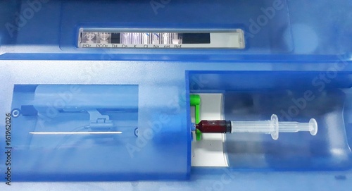 Closeup front view of Blood gas analysis machine with syringe of blood sample.