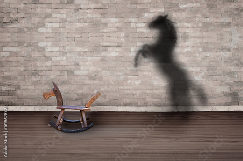 The concept of the hidden potencial.Toy horse in the room which casts a shadow on the wall.