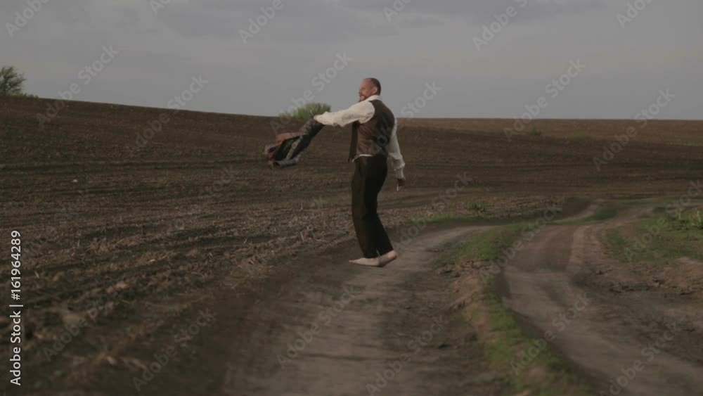 Male in a classic costume in nature. A man in a suit is glad and dances in the field.
Male in a classic costume in nature. A man in a suit is glad and dances in the field.
