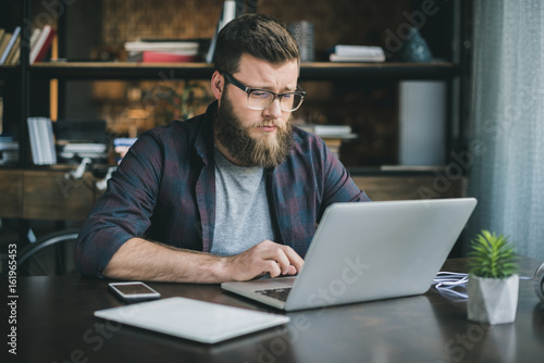 young caucasian man working on laptop while sitting at home