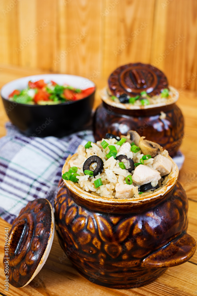 Rice with chicken, mushrooms and olives on wooden background