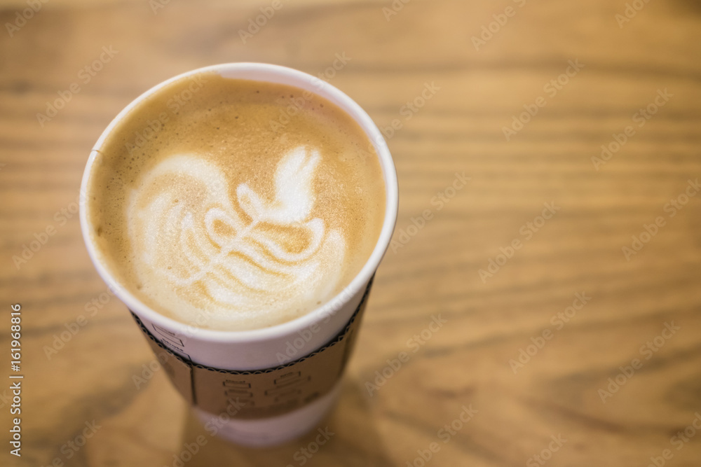 A paper cup coffee latte art on the wooden table (selective focus) A paper cup coffee latte art on the wooden table (selective focus)
