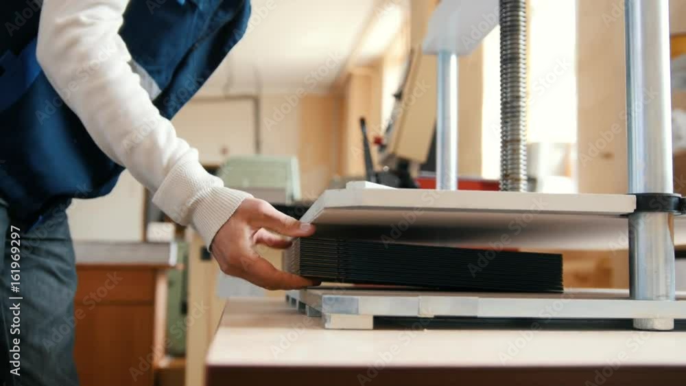 Printing process - worker inserts paper sheets in industrial press