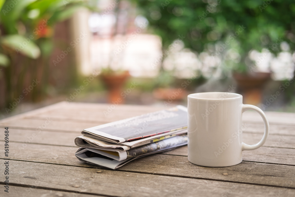 Φωτογραφία Cup of hot coffee with newspaper on wooden table in garden morning