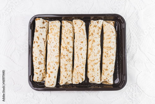 Pancakes stuffed in a dark brown tray on a white lace background