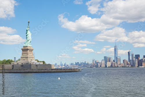 Statue of Liberty island and New York city skyline in a sunny day  white clouds
