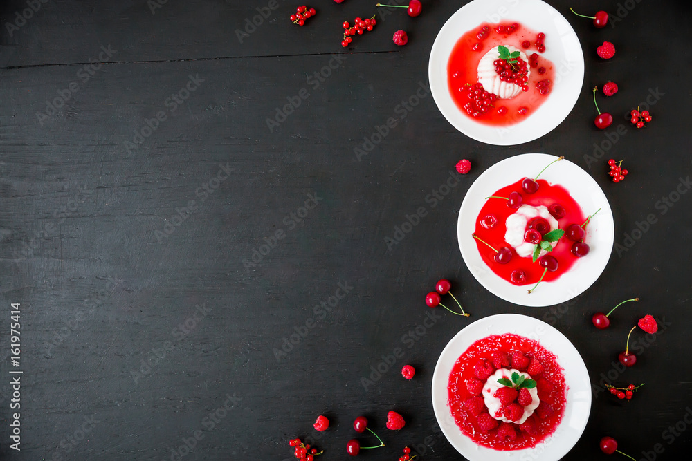 Panna cotta with fruit syrup in a plate on a dark background and tasty berries. Flat lay. Top view. Traditional italian dessert. Panna cotta with fruit syrup in a plate on a dark background and tasty berries. Flat lay. Top view. Traditional italian dessert.