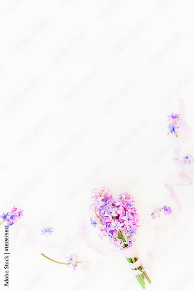 Bouquet of pink flowers and purple shabby tapes on white background. Flat lay, top view. Beauty background