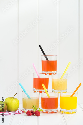 Collage of glasses with fresh delicious smoothie juice and straw on board background colourful for kids party