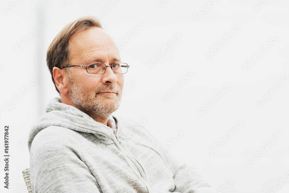 Outdoor portrait of 50 year old man wearing grey hoody and eyeglasses