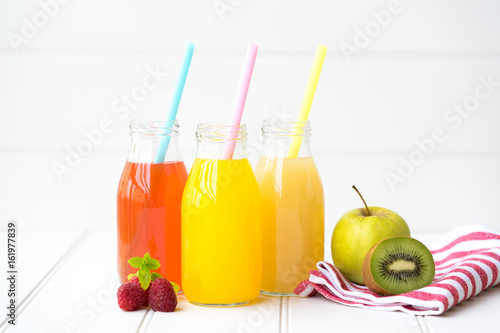 Collage of glasses with fresh delicious smoothie juice and straw on board background colourful for kids party