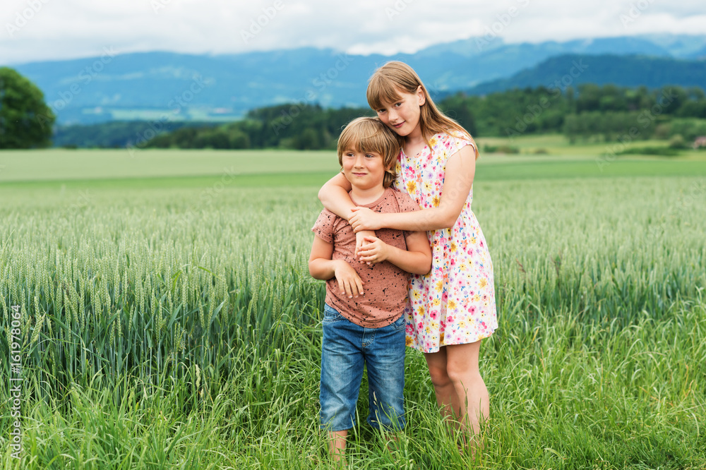 Two adorable kids playing together in summer wheat field Two adorable kids playing together in summer wheat field