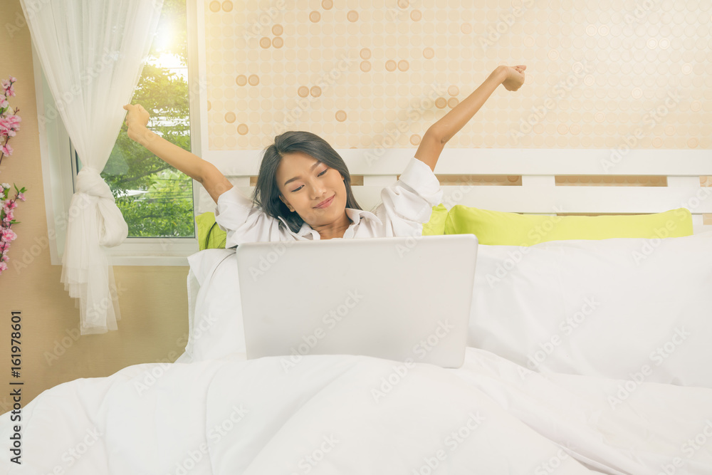 Woman stretching in bed and used notebook after wake up in early mornig. Woman stretching in bed and used notebook after wake up in early mornig.