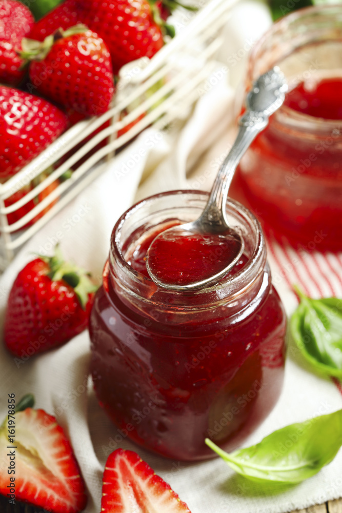 Homemade strawberry jam with basil in a glass jar and fresh strawberries on table Homemade strawberry jam with basil in a glass jar and fresh strawberries on table