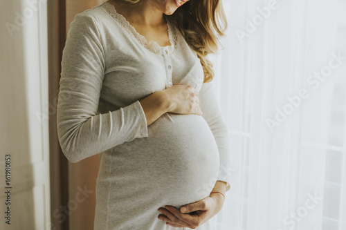 Canvastavla Young pregnant woman by the window