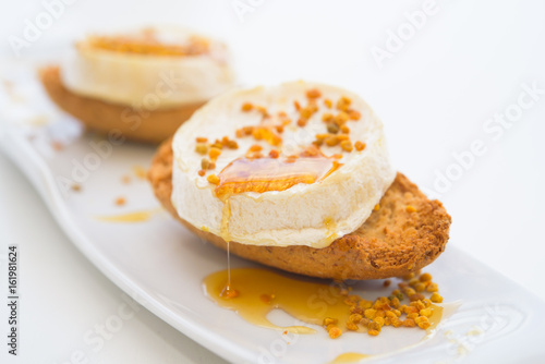  Goat cheese with honey and pollen on the bread, macro, isolated