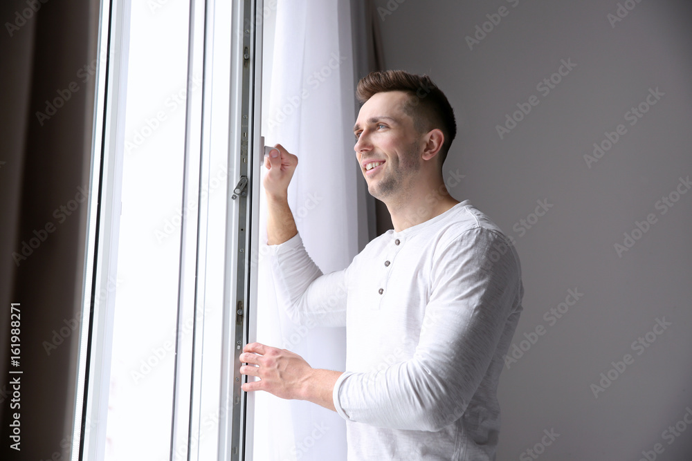 Smiling man opening white plastic window