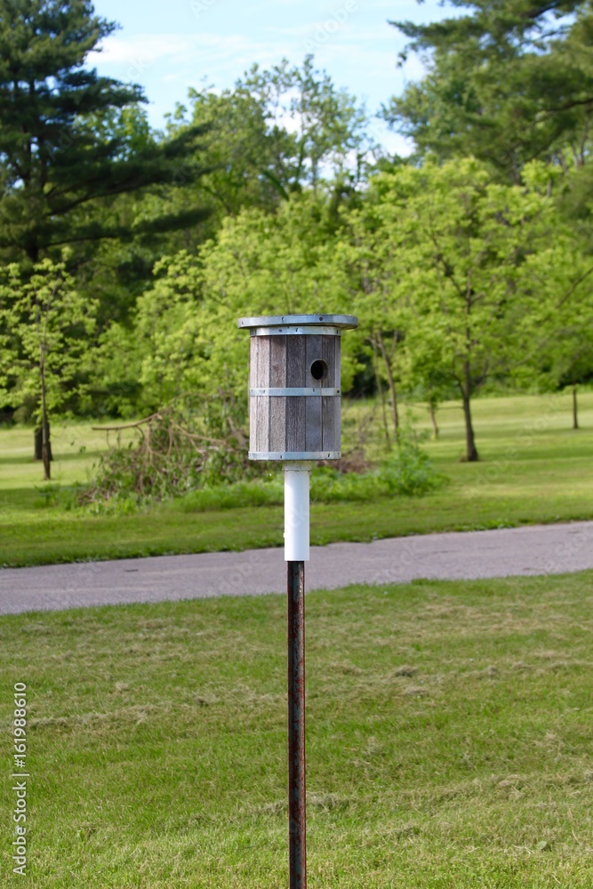 The round wooden birdhouse in the grass. The round wooden birdhouse in the grass.