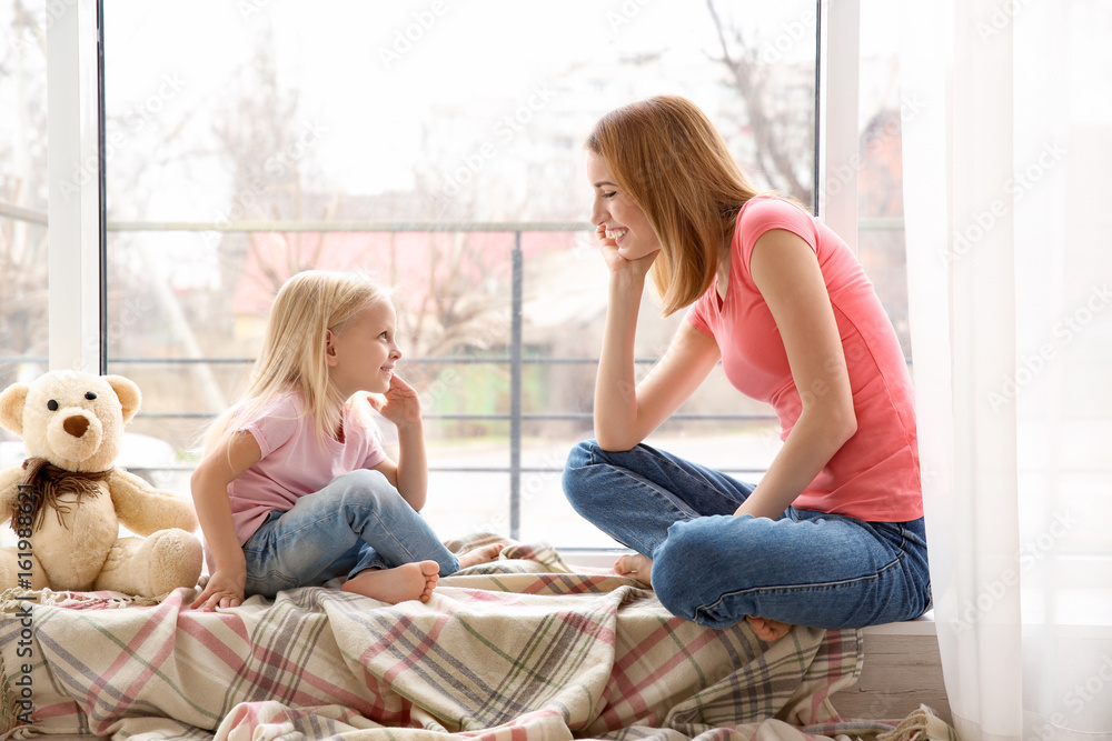 Mother and daughter sitting on windowsill Mother and daughter sitting on windowsill