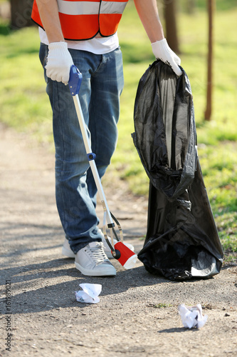 Fotografie Young volunteer picking up litter in park