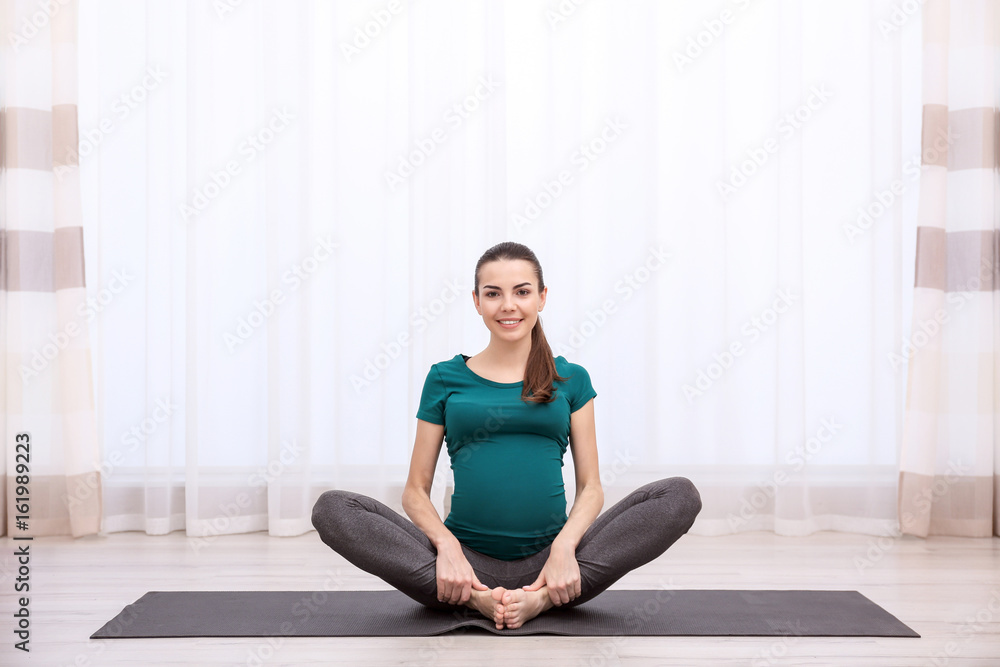 Beautiful pregnant woman doing exercise indoors