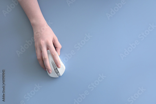 Female hand holding computer mouse on grey background