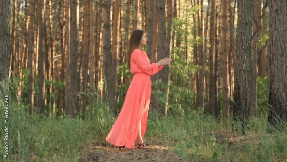 Girl in evening dress in red color in the forest Girl in evening dress in red color in the forest