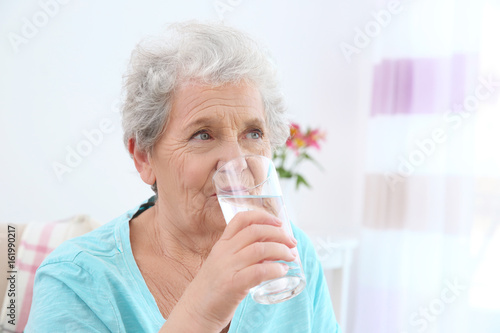 Elderly woman drinking wate...