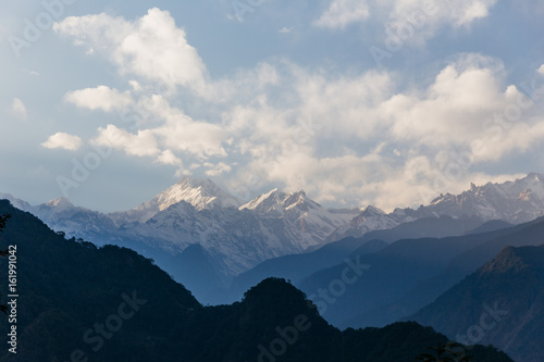 Kangchenjunga mountain with clouds above. Among green hills that view in the evening in North Sikkim, India.