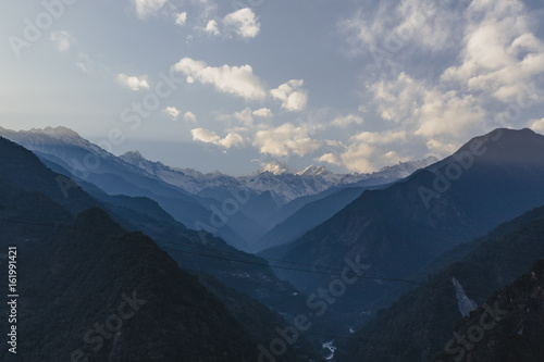 Kangchenjunga mountain with clouds above. Among green hills that view in the evening in North Sikkim, India.