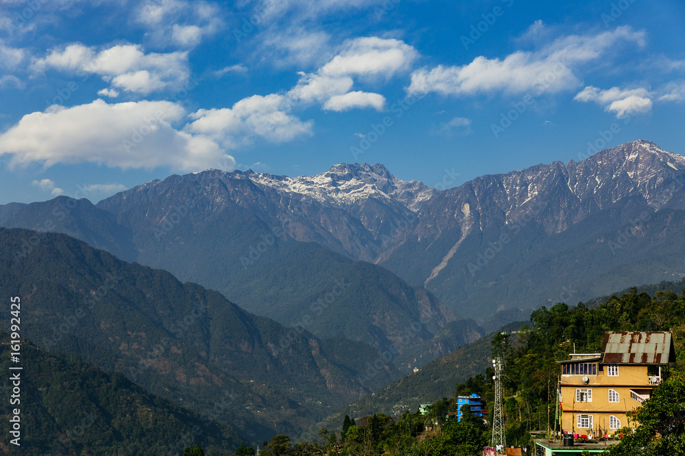 Kangchenjunga mountain with clouds above and green roof house. Among green hills that view in the evening in North Sikkim, India. Kangchenjunga mountain with clouds above and green roof house. Among green hills that view in the evening in North Sikkim, India.