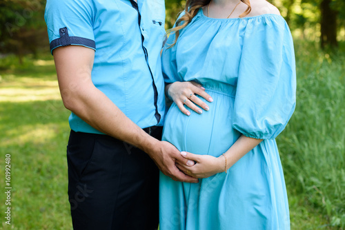 Quadro em tela Careful husband is tenderly hugging his pregnant wife and his hands lay on her b
