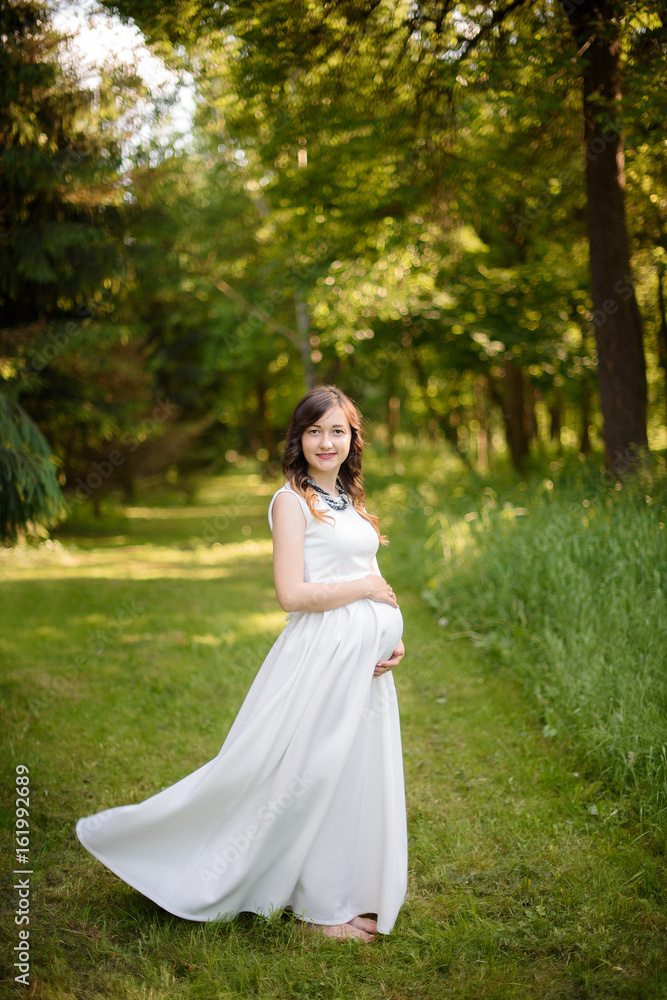 Outdoor portrait of young pregnant woman in summer nature