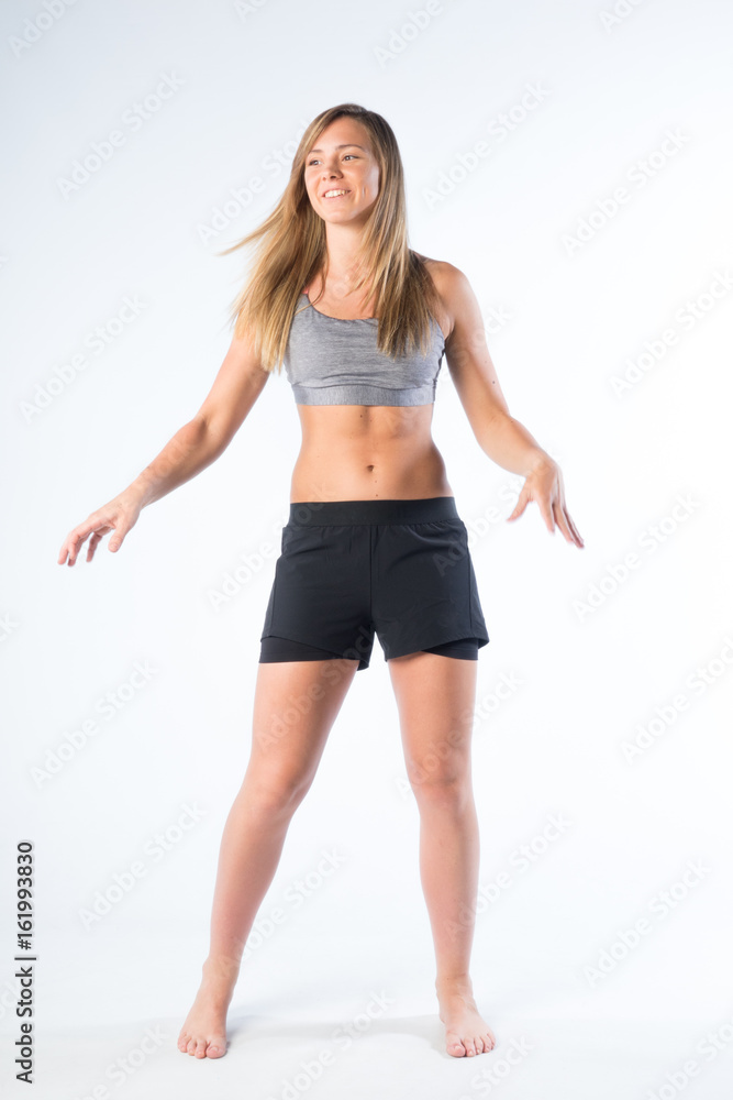 giovane ragazza bionda con fisico sportivo fa ginastica in studio su fondale bianco giovane ragazza bionda con fisico sportivo fa ginastica in studio su fondale bianco