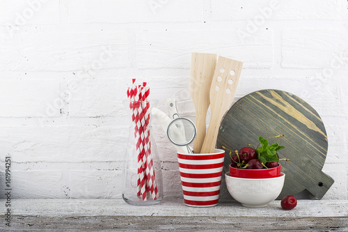 A simple kitchen still life against a white brick wall: cutting board, cooking equipment, ceramics. Horizontal photo