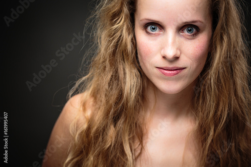 Studio glamour portrait of a pretty, young woman with lovely curly hair