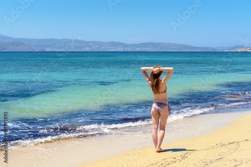 Beautiful young and happy woman having a good time on a summer beach. Agia Anna beach. Naxos, Cyclades Islands, Greece.