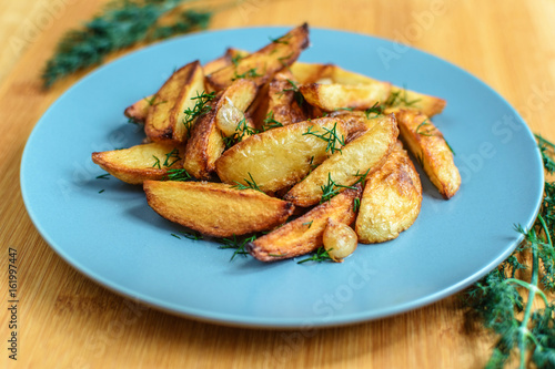 Roasted potatoes with salt pepper and cumin on wooden background