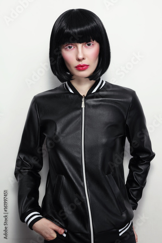 Beautiful slim brunette with bob haircat and stylish makeup in vintage leather jacket