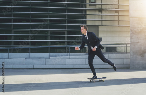 Businessman on a skateboard in urban area