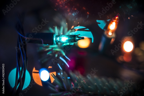 christmas tree decoraion closeup with glowing lights garlands and colorful bokeh