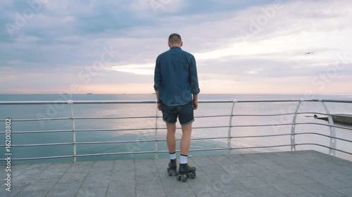 a young caucasian man roller skating with quad skates near the sea, photo