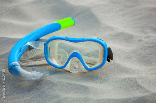 The blue mask for diving and the tube lie on the beach, on the sand. The concept of tourism and travel.