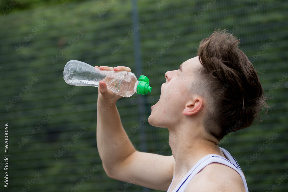 Fototapeta premium Teenage boy squirting water into his mouth