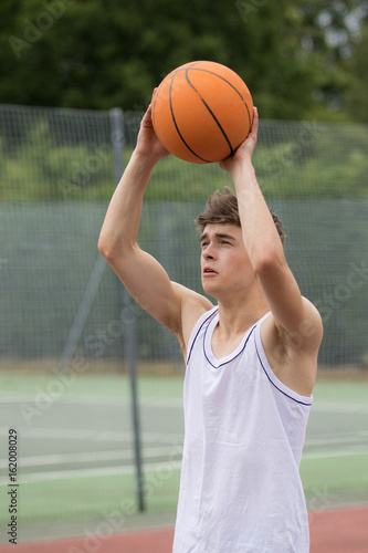 Teenage boy shooting a hoop on a basketball court © Ben Gingell