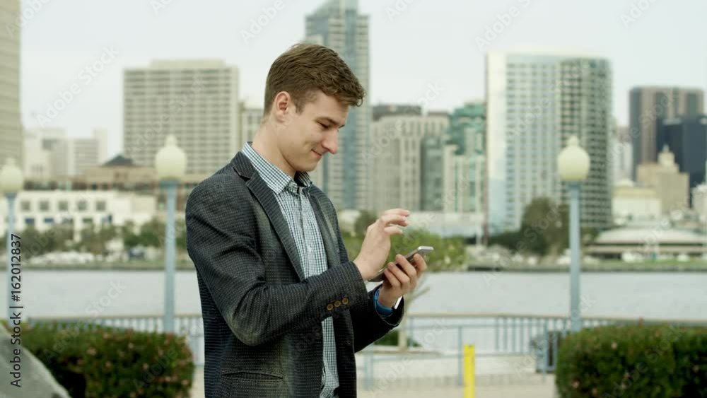 Businessman is sending a text message while standing on a street in Coronado Businessman is sending a text message while standing on a street in Coronado